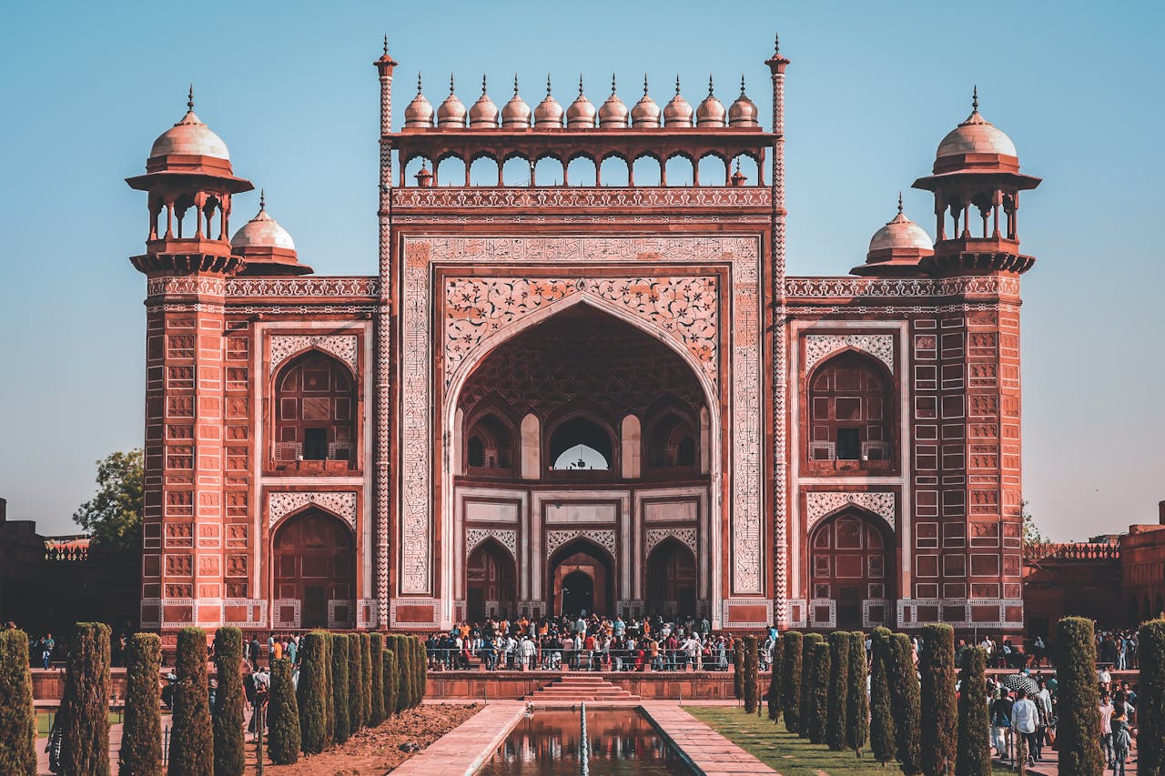 Magnificent scenery of facade of Taj Mahal with crowd of tourists near entrance on sunny day with blue sky in Agra
